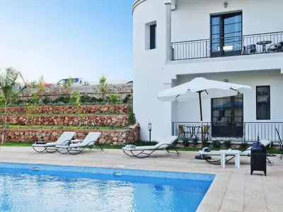 a house with two chairs and an umbrella next to a pool at Villa Agapanthe in Fès