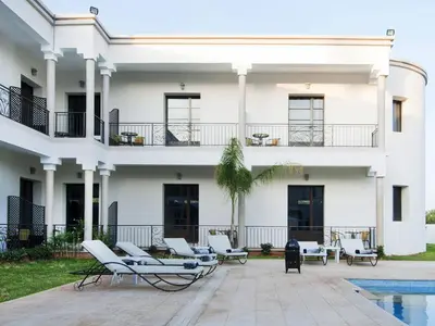 a white building with lounge chairs and a pool at Villa Agapanthe in Fès