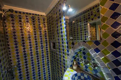 a tiled bathroom with a sink and a mirror at Le Cèdre D'argent in Fès