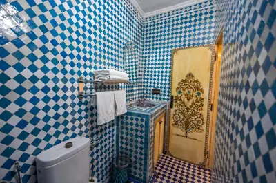 a bathroom with blue and white tiled walls and a toilet at Le Cèdre D'argent in Fès