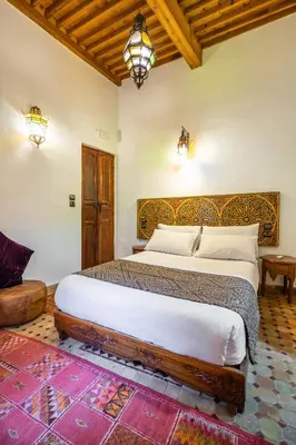 a bedroom with a large bed with a wooden headboard at Le Cèdre D'argent in Fès