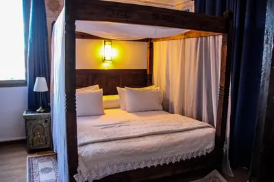 a bedroom with a canopy bed with white sheets and pillows at Hotel La Perle du Sud in Ouarzazate