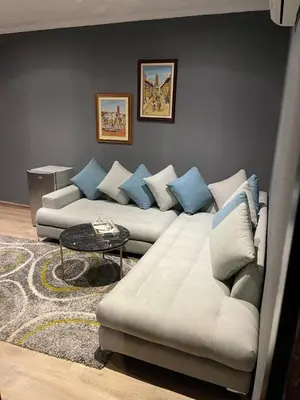 a living room with a white couch and blue pillows at Hotel La Perle du Sud in Ouarzazate