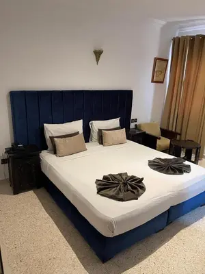 a bedroom with a large bed with a blue headboard at Hotel La Perle du Sud in Ouarzazate