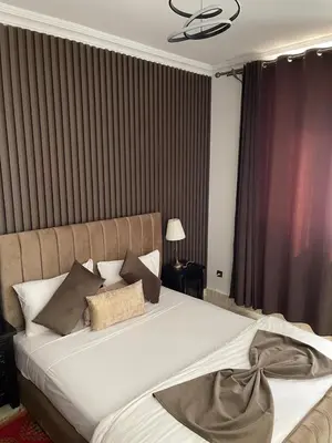 a bedroom with a large white bed with pillows at Hotel La Perle du Sud in Ouarzazate