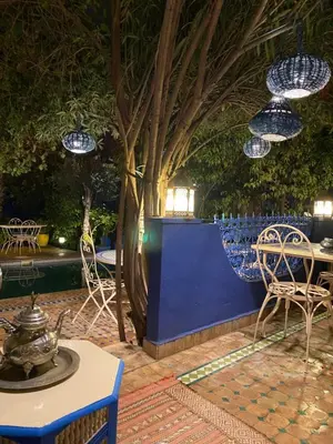 a patio with chairs and tables and blue walls at Riad Jean Claude in Fès