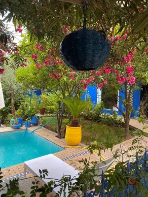a swimming pool with a yellow vase with pink flowers at Riad Jean Claude in Fès