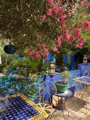 a patio with tables and chairs and pink flowers at Riad Jean Claude in Fès