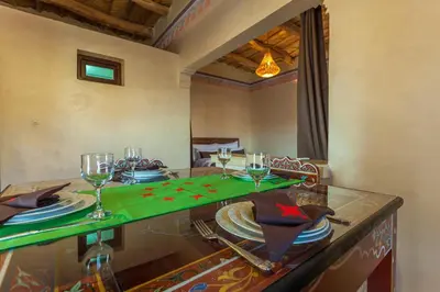 a dining room with a table with plates and wine glasses at Kasbah Tizzarouine in Boumalne