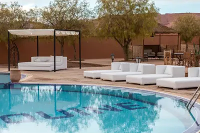 a swimming pool with white chairs and a gazebo at Kasbah Tizzarouine in Boumalne