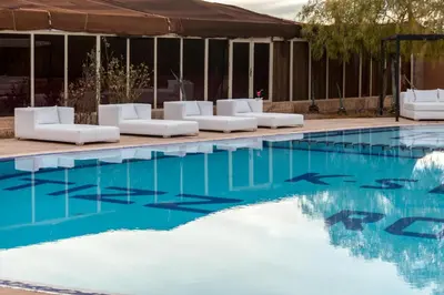 a swimming pool with white lounge chairs and blue water at Kasbah Tizzarouine in Boumalne