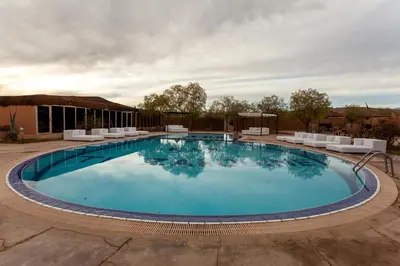 a large swimming pool with white lounge chairs around it at Kasbah Tizzarouine in Boumalne