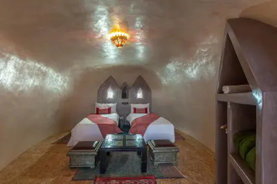 a bedroom with two beds and a table in a room at Kasbah Tizzarouine in Boumalne