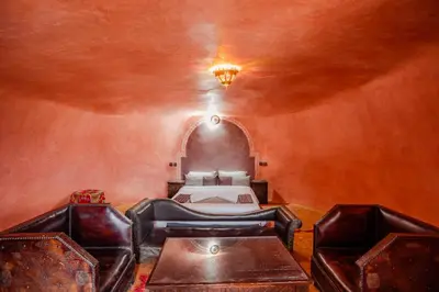 a bedroom with a bed and two leather chairs at Kasbah Tizzarouine in Boumalne