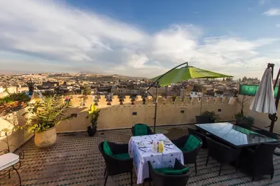 a patio with a table and a view of a city at Riad Les Remparts De Fès in Fès