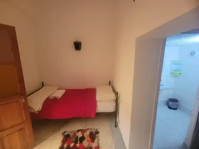 a small bedroom with a bed with a red blanket at Riad Dar Lemdrssa in Fès