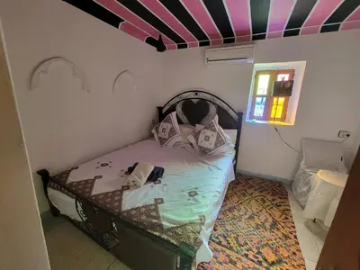 a small bed in a room with a striped ceiling at Riad Dar Lemdrssa in Fès