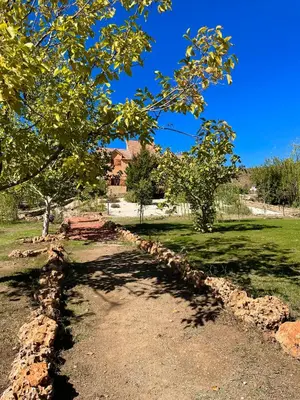 a stone path with trees and a house in the background at Ferme D’hôte La Vallée in Azrou