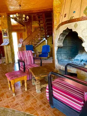 a living room with a large stone fireplace and chairs at Ferme D’hôte La Vallée in Azrou