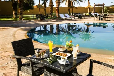 a table with food and drinks next to a pool at Erfoud Palace in Erfoud