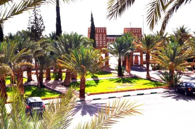 a view of a park with palm trees and a building at Erfoud Palace in Erfoud