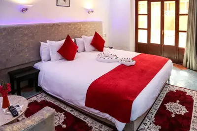 a bedroom with a large white bed with red pillows at Erfoud Palace in Erfoud