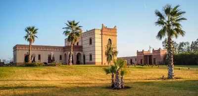 a building with palm trees in front of it at Villa Diaf Johanne in Aït Ourir