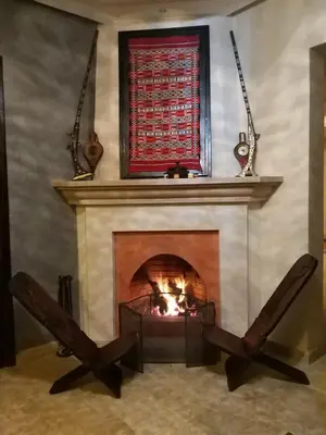 a living room with a fireplace with a red window at Villa Diaf Johanne in Aït Ourir
