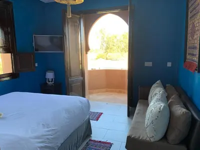a bedroom with a bed and a couch and a window at Villa Diaf Johanne in Aït Ourir