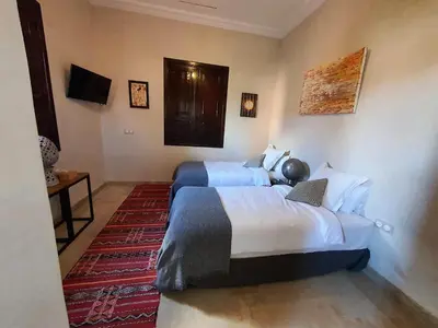 a hotel room with two beds and a rug at Villa Diaf Johanne in Aït Ourir