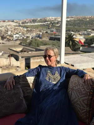 a woman in a blue dress sitting on a couch at Dar Settash in Fès