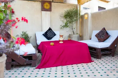 a patio with a red table and two chairs at Dar Settash in Fès