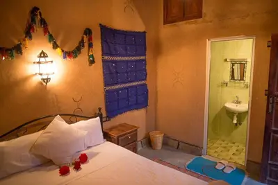 a bedroom with a bed and a bathroom with a sink at Maison D' hôtes Ait Hmid in Nkob