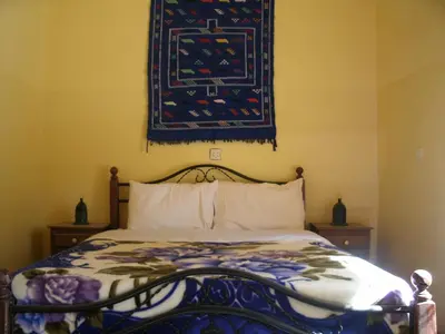 a bedroom with a bed with a rug on the wall at Maison D' hôtes Ait Hmid in Nkob