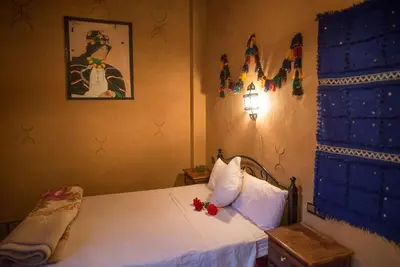 a bedroom with a bed with red flowers on it at Maison D' hôtes Ait Hmid in Nkob