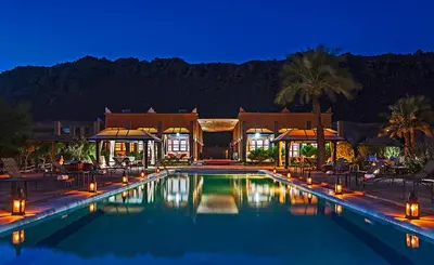 a swimming pool with lights in front of a house at Hotel Bab Rimal - Your Foum Zguid Escape in Foum Zguid