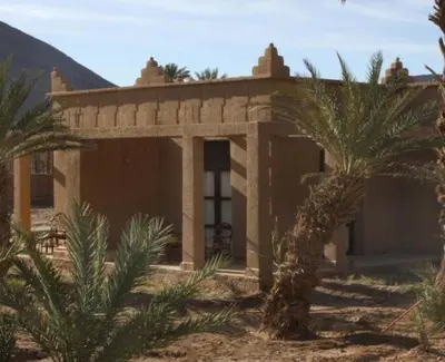 a small house with palm trees in front of it at Hotel Bab Rimal - Your Foum Zguid Escape in Foum Zguid