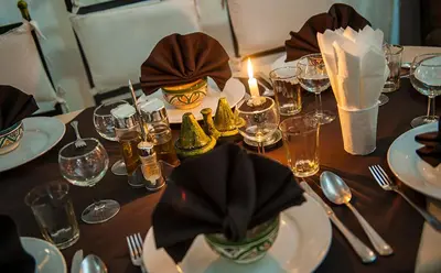 a table with plates and glasses and a candle on it at Hotel Bab Rimal - Your Foum Zguid Escape in Foum Zguid
