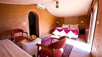 a bedroom with a bed and a table and chairs at Hotel Bab Rimal - Your Foum Zguid Escape in Foum Zguid