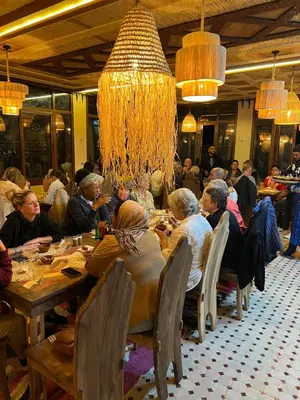 a group of people sitting at a table in a restaurant at Gîte d'étape Tamaloute in Bou Tharar