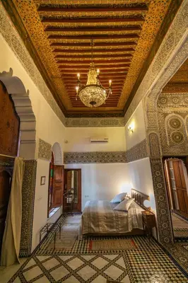 a bedroom with a bed and a ceiling with a chandelier at Ryad Mabrouka in Fès