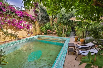 a swimming pool in a yard with chairs and flowers at Ryad Mabrouka in Fès