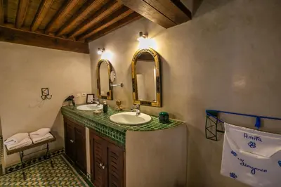 a bathroom with a sink and two mirrors at Ryad Mabrouka in Fès