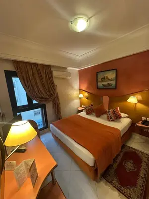 a hotel room with a large bed and a desk at Hotel Mounia in Fès