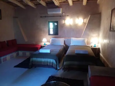 a bedroom with two beds and a red couch at La Kasbah d'Ouzoud in Ouzoud