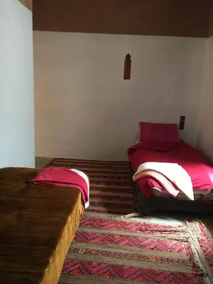 a bedroom with two beds and a rug at Maison D'hôtes Dar Afra in Aït Ziri