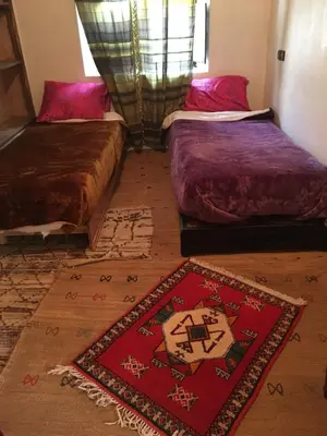 two beds in a room with a rug on the floor at Maison D'hôtes Dar Afra in Aït Ziri