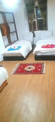 two beds in a room with a rug on the floor at Maison D'hôtes Dar Afra in Aït Ziri