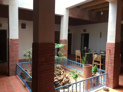 a building with a courtyard with plants and a fence at Maison D'hôtes Dar Afra in Aït Ziri