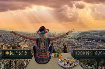 a woman sitting on a table looking out over a city at Palais Faraj Suites & Spa in Fès